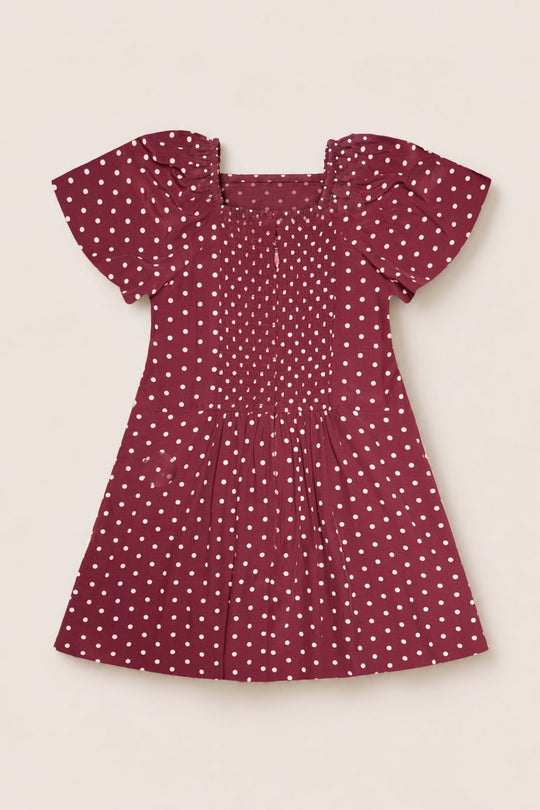 A short-sleeve Teen Blakely Dress in Cranberry Dainty Dot by Ivy City Co, featuring white polka dots, petal sleeves, and a smocked bodice. This midi-length dress is laid flat on a light background.