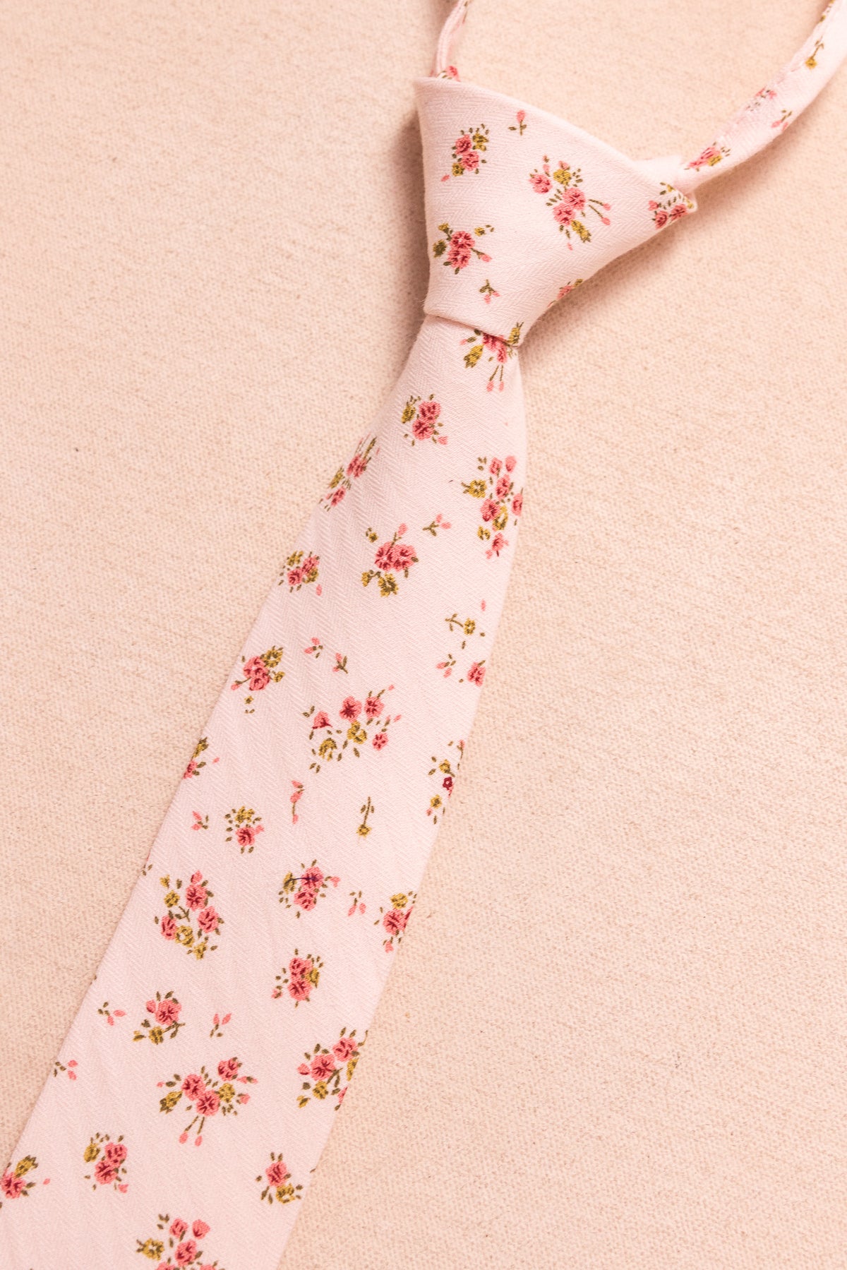 The Ivy City Co Ties in Madeline Pink Floral feature small pink and green floral designs on light pink fabric—perfect for coordinating with boys’ bow ties or other matching family accessories.