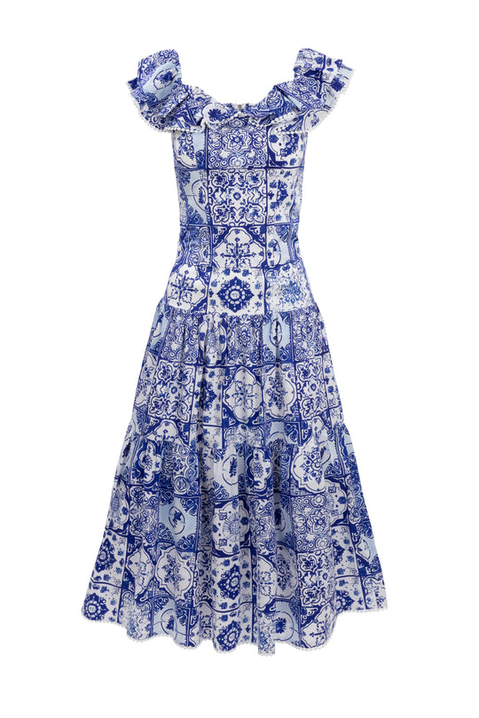 The Rosina Blouse in Blue Tile by Ivy City Co features a blue and white patchwork pattern inspired by intricate tile designs, with flutter sleeves for a stylish touch.