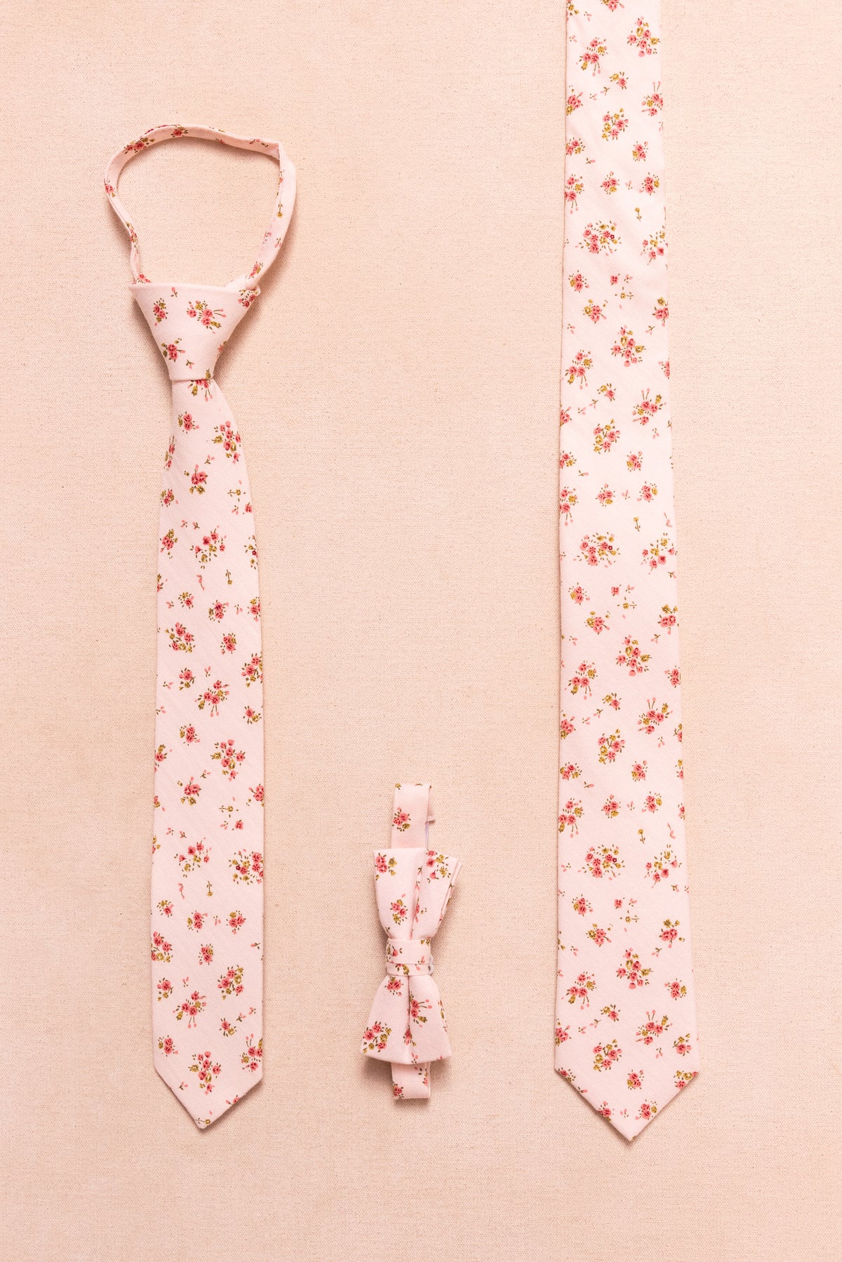The Ivy City Co Ties in Madeline Pink Floral—available as a tied necktie, untied necktie, and boys bow tie—feature vertical red florals on beige, ideal for matching family accessories.