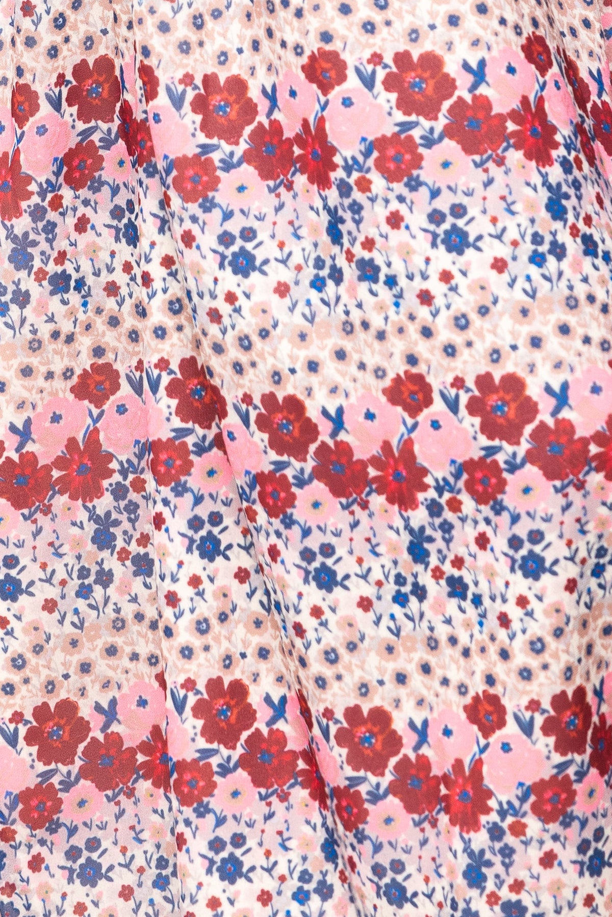 Detailed view of the fabric from Ivy City Co’s Hayden Dress in Lush Garden, showcasing a maternity-friendly design with red, pink, and blue floral motifs on a light background, arranged in horizontal stripes accented by scattered small blue and tan dots.