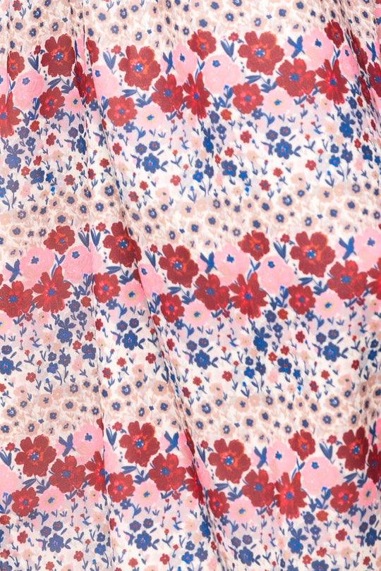 Detailed view of the fabric from Ivy City Co’s Hayden Dress in Lush Garden, showcasing a maternity-friendly design with red, pink, and blue floral motifs on a light background, arranged in horizontal stripes accented by scattered small blue and tan dots.