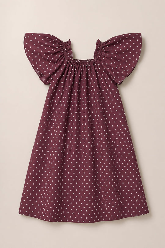 The Ivy City Co Teen Blakely Dress in Aubergine Ditsy Dot—a maroon viscose midi dress with white polka dots, short flutter sleeves, and a gathered neckline—is displayed against a plain light background.