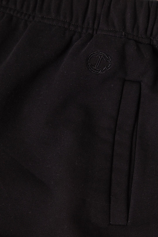 Close-up of the Mini Micah Jogger Sweatpants in Black by Ivy City Co, showcasing soft black fabric with an elastic waistband, a side pocket, and a small circular embroidered logo near the pocket—designed with inspiration from classic girls’ cotton joggers.