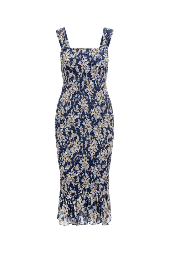 Ivy City Co’s Mira Dress in Gilded Vine features a navy blue, sleeveless midi design with a square neckline, fitted silhouette, gold floral lace overlay inspired by the Gilded Vine collection, and a ruffled hem.