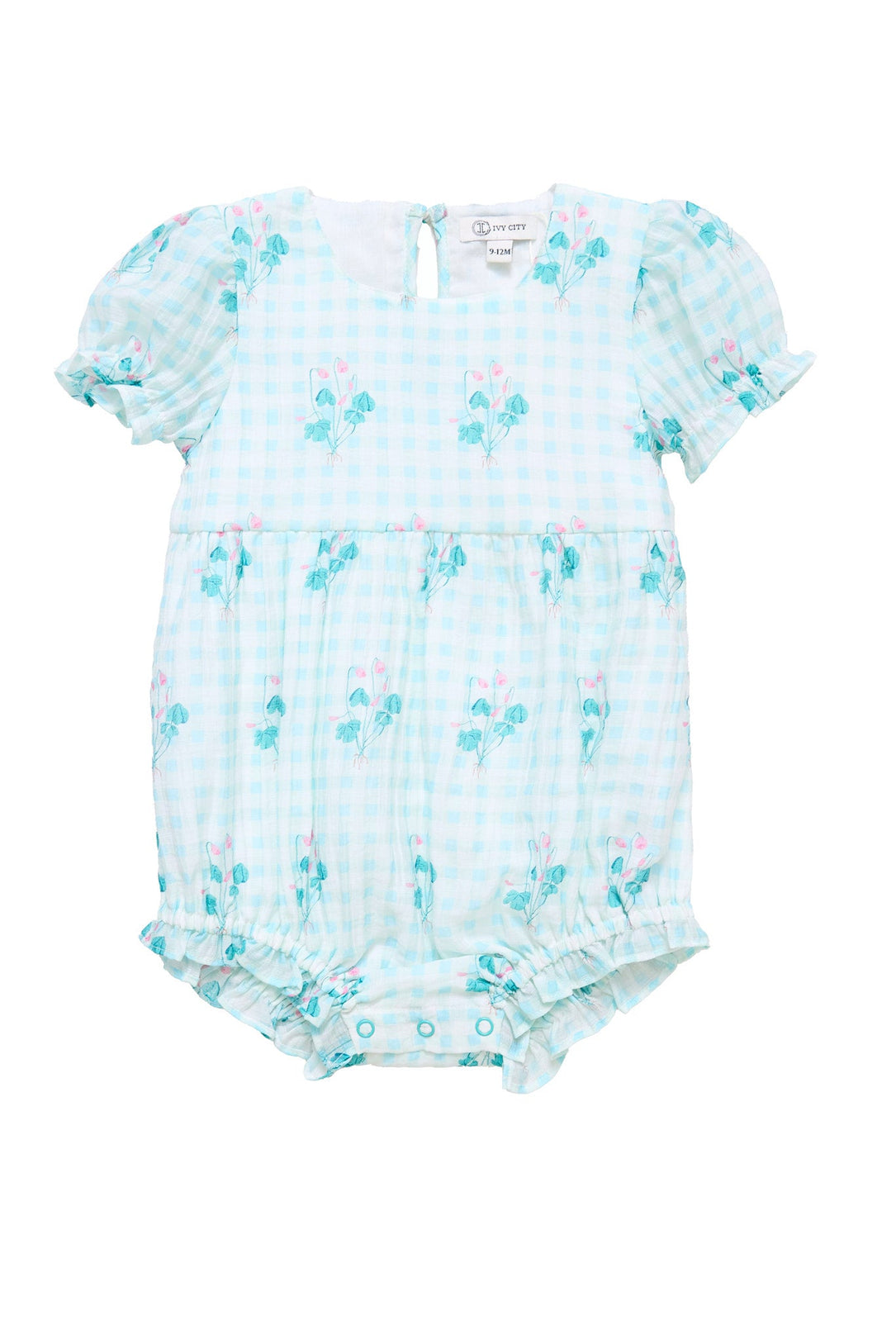 The Ivy City Co Baby Jessie Romper in Bloom Gingham features a light blue and white gingham pattern accented with a delicate floral print, short puff sleeves, a gathered waist, and easy snap buttons at the bottom—making it a charming choice for an Easter outfit.