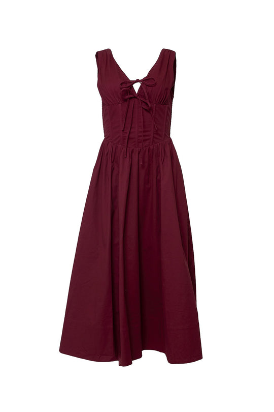 The Kayla Dress in Burgundy by Ivy City Co is a sleeveless midi dress with a fitted bodice, bow detail at the chest, and a subtle v-neckline for an elegant flair. Featuring a gathered corset waist that enhances your silhouette, this ankle-length dress flows into a flared skirt—perfect for any occasion.