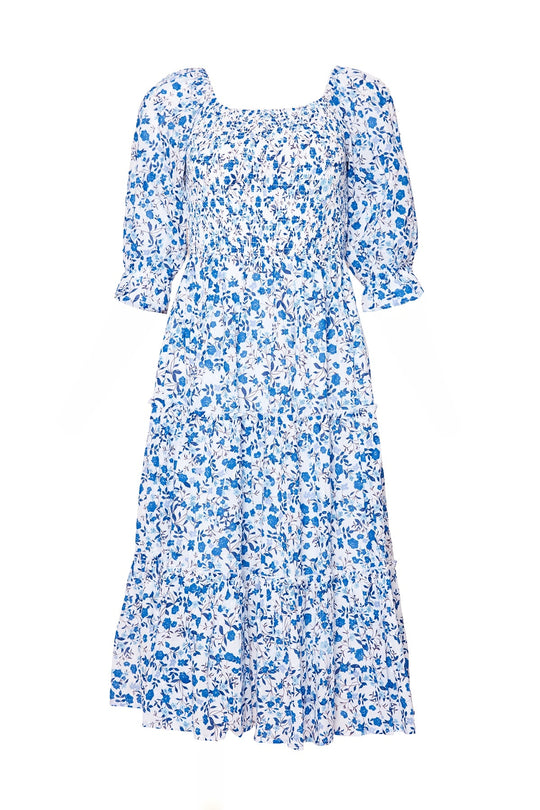 The Madeline Dress in Ditsy Cobalt Floral by Ivy City Co is a white cotton floral dress with a blue print, featuring puffed elbow-length sleeves, a fitted smocked bodice, and a tiered skirt—this smocked midi dress offers both comfort and style for any occasion.