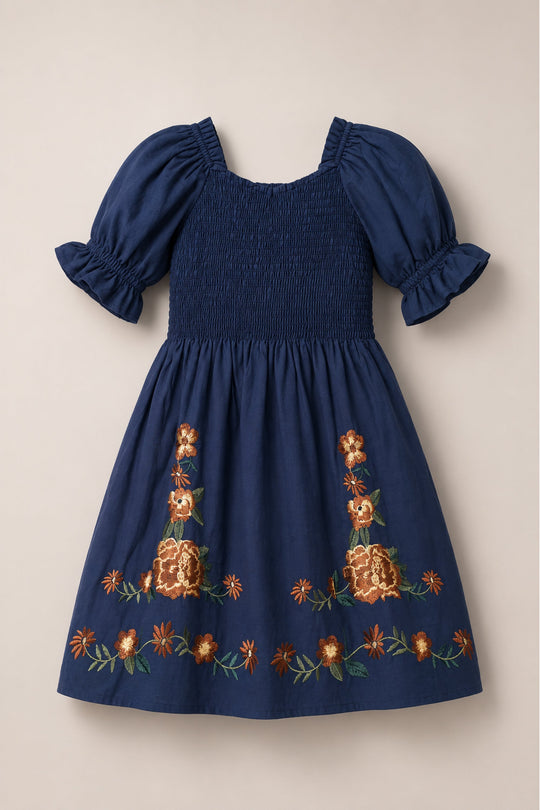 The Mini Teagan Dress in Navy Embroidered Fall Floral by Ivy City Co features balloon sleeves, a smocked bodice with ruffled cuffs, and orange and yellow floral embroidery accenting the skirt and hem.
