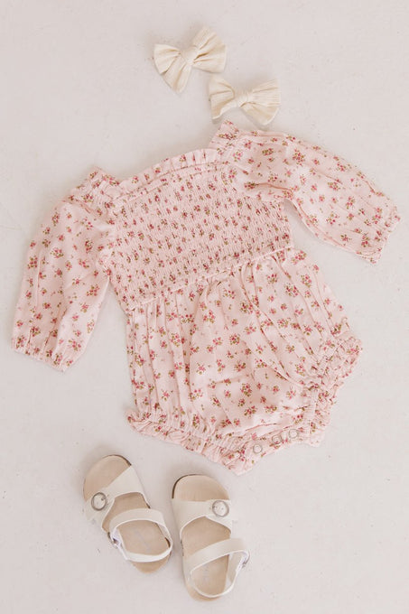 The Ivy City Co Baby Madeline Romper in Pink, paired with cream hair bows and white sandals, is arranged on a light surface—an adorable puff sleeve set perfect for your little one.