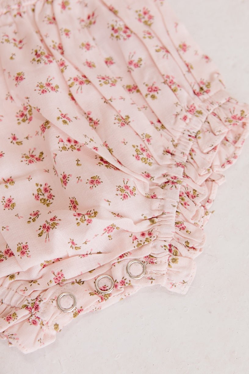 The Ivy City Co Baby Madeline Romper in Pink features a small floral print, ruffled edges, and metal snap buttons—perfect for pairing with your favorite bloomers or wearing on its own.